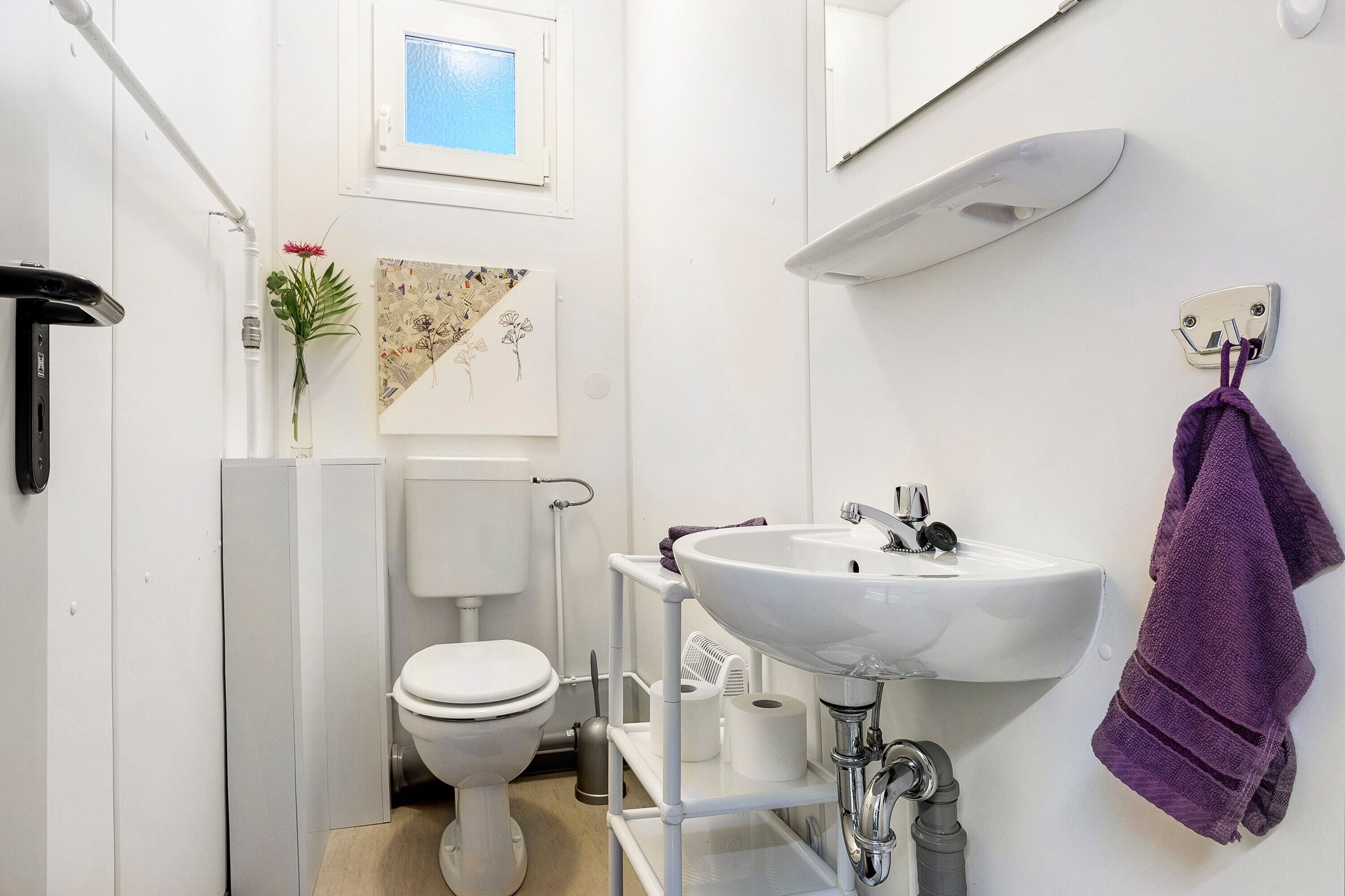 A bathroom with a toilet, sink, and a towel rack.