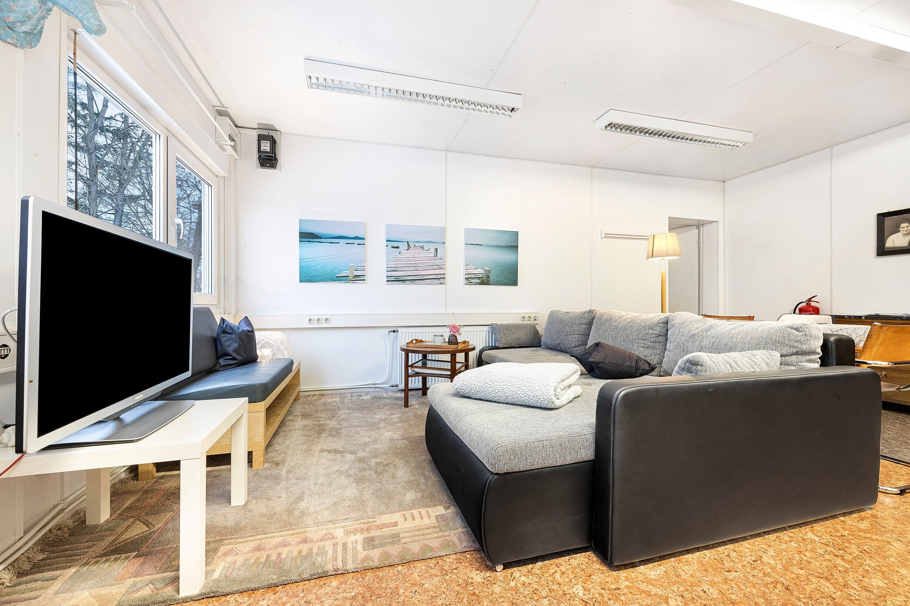 Ein modernes Wohnzimmer mit Flachbildfernseher, einer Couch, einem kleinen Tisch und einem Teppich.