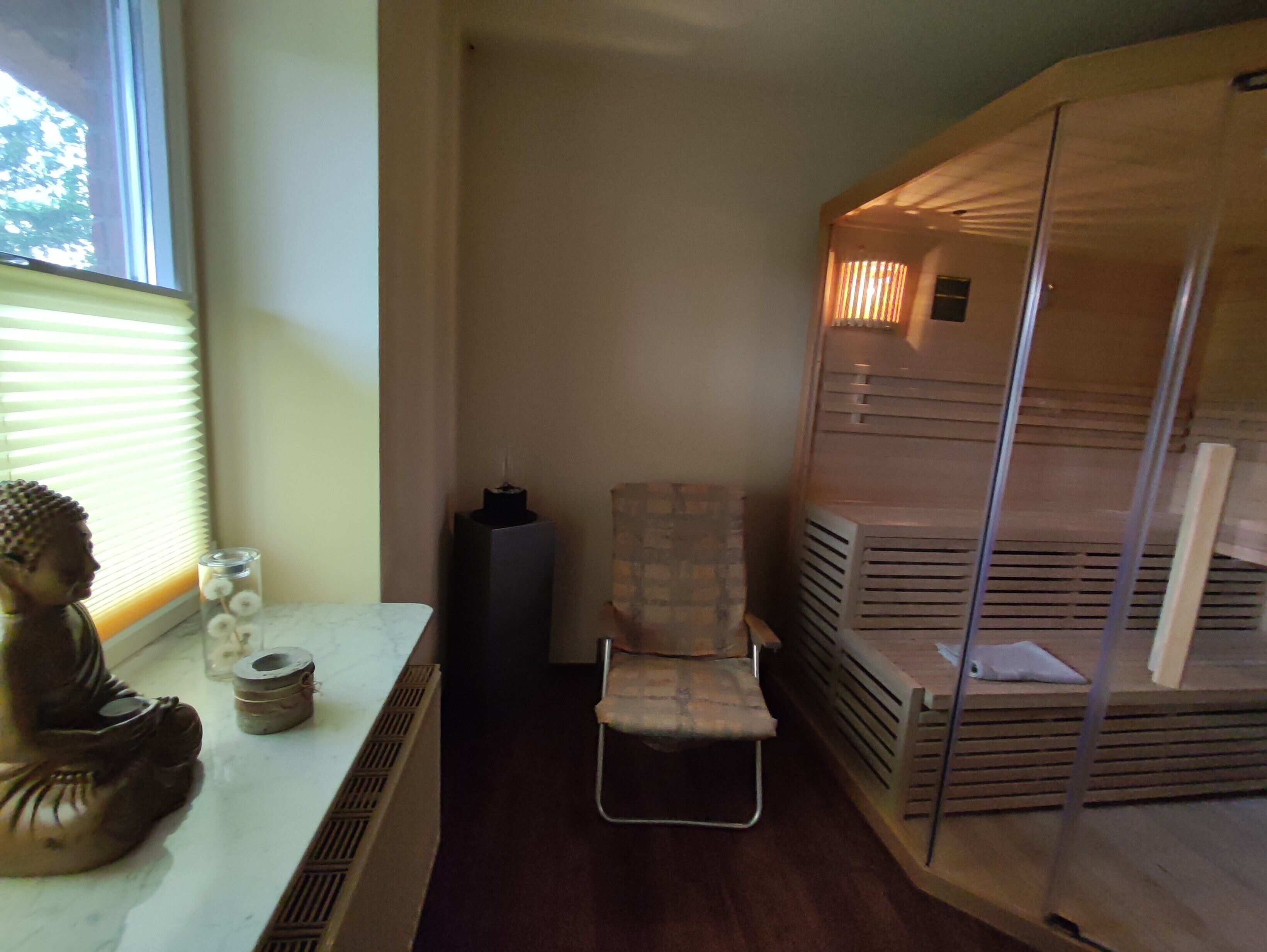 A room with a window, a statue, a chair, and a storage unit.