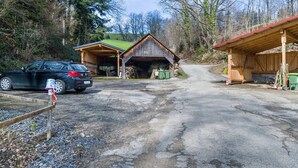 Une propriété rurale avec une grange en bois, une voiture garée devant et une allée gravillonnée.