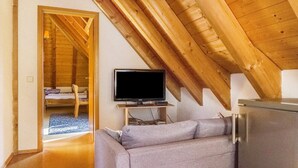 Une pièce équipée d’une télévision, d’un canapé, d’un réfrigérateur et dont le plafond est en bois.