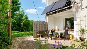 A patio with a table and chairs, a wooden fence, and a solar panel on the building. - Apartment 'Ferienwohnung Am Seebach, 80 Qm' with Private Terrace and Wi-Fi (Titisee-Neustadt)