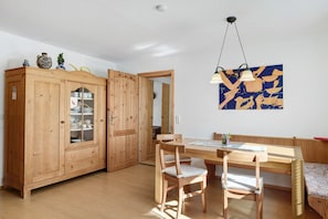 Une table à manger en bois avec des chaises, un meuble avec des portes en verre et une œuvre d’art accrochée au mur.