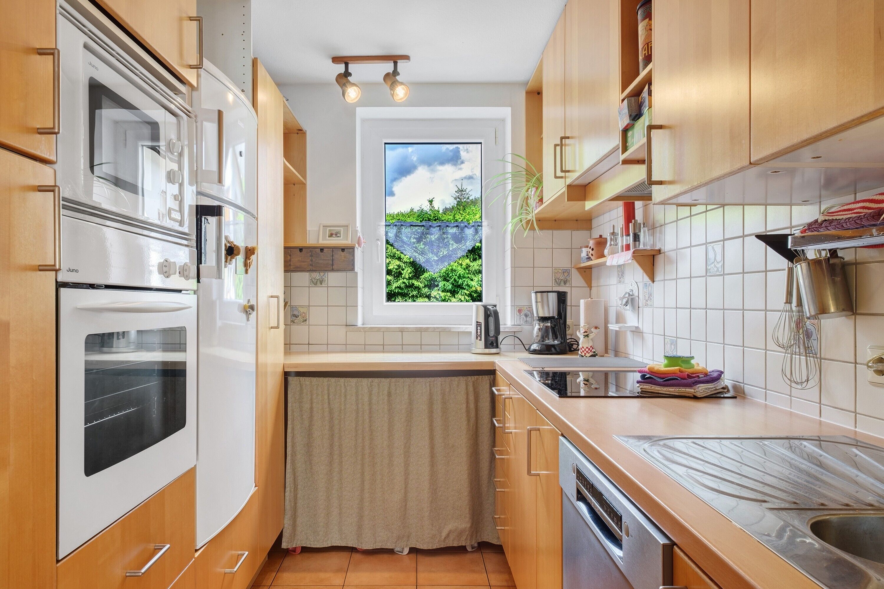 Eine kompakte Küche mit eingebauten Geräten, einem Fenster mit Blick und Holzschränken.
