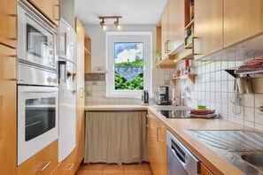 Eine kompakte Küche mit eingebauten Geräten, einem Fenster mit Blick und Holzschränken.