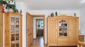 A wooden cabinet with glass doors, a wooden table, and a plant. - Apartment 'Ferienwohnung Am Seebach, 80 Qm' with Private Terrace and Wi-Fi (Titisee-Neustadt)