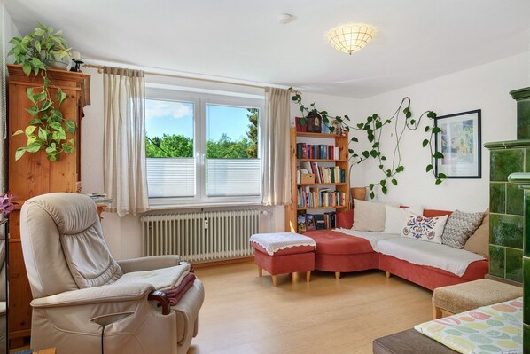 A living room with a sofa, armchair, and ottoman, a bookshelf, and a radiator.