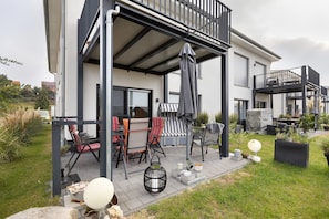 Una casa moderna con patio, mobili da esterno e un balcone.
