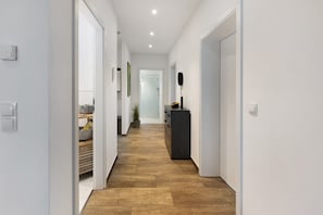 A hallway with a wooden floor, white walls, and a black cabinet. - Apartment "Spanier" with Lake View, Private Terrace and Wi-Fi (Muldestausee OT Pouch)