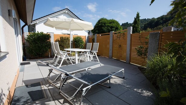 Eine Terrasse mit Tisch, Stühlen und Sonnenschirm.