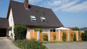 Ein zweistöckiges Haus mit geneigtem Dach, einem Schornstein und zwei Dachfenstern.