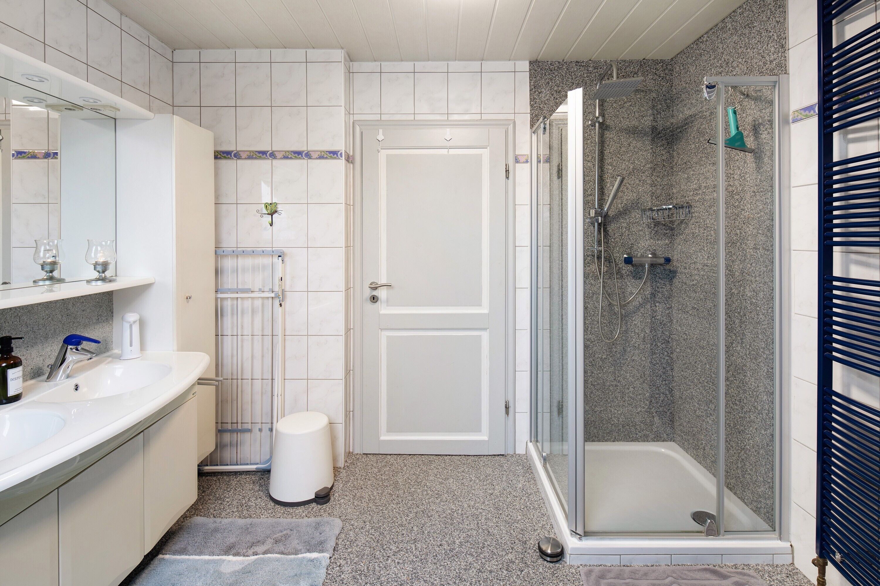 A bathroom with a shower, two sinks, a toilet, and a mirror.