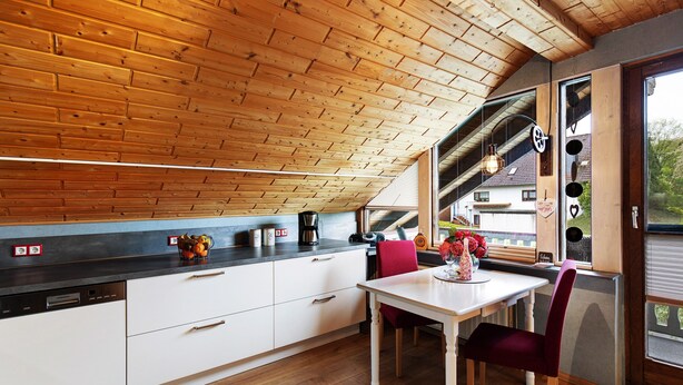 A kitchen with wooden ceiling, white cabinets, and a dining table with chairs. - Apartment "Landharmonie Knüll" with Private Terrace, Balcony & Wi-Fi (Frielendorf)
