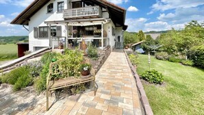 A two-story house with a balcony, a paved pathway leading to the entrance, and a garden area. - Apartment "Landharmonie Knüll" with Private Terrace, Balcony & Wi-Fi (Frielendorf)
