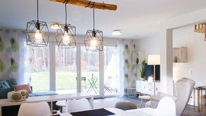 Un salon moderne avec un coin repas, de grandes fenêtres et une vue sur l’extérieur.
