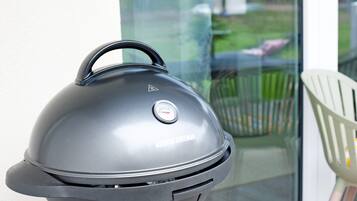 Una griglia George Foreman con termometro digitale, una porta in vetro e una sedia bianca sullo sfondo.