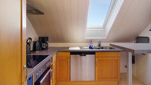 A kitchen with wooden cabinets, a dishwasher, a stove, and a skylight.
