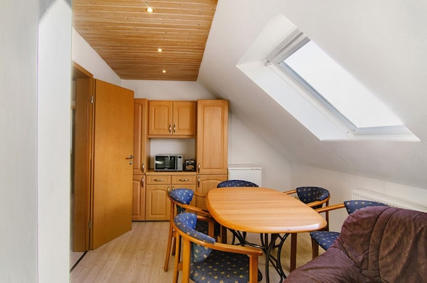 A compact kitchen with wooden cabinets, a microwave, and a dining area with a table and chairs.