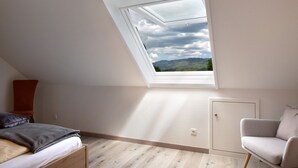 Une pièce avec un puits de lumière, un lit, une chaise et une armoire.