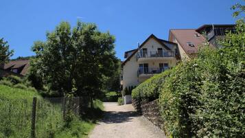 A residential area with a gravel path leading to a two-story house with a balcony.