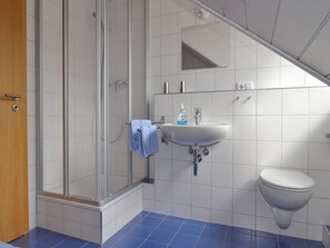 Une salle de bain avec une douche, un lavabo et des toilettes.