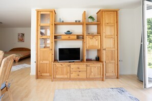 A wooden entertainment unit with a flat-screen TV, shelves, and cabinets.