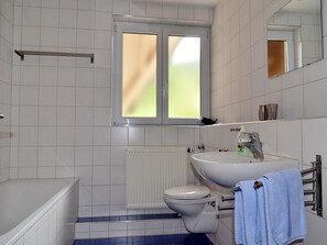 A bathroom with a bathtub, toilet, sink, and a window with blinds.