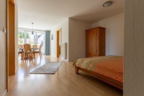 A bedroom with a bed, wooden wardrobe, and a dining area with chairs and a table. - Apartment '1 O G' with Lake View, Balcony and Wi-Fi (Bodman-Ludwigshafen)