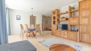 A modern living room with a dining area, wooden furniture, a TV, and a grey sofa. - Apartment '1 O G' with Lake View, Balcony and Wi-Fi (Bodman-Ludwigshafen)