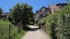 A residential area with a gravel path leading to a two-story house with a balcony. - Apartment '1 O G' with Lake View, Balcony and Wi-Fi (Bodman-Ludwigshafen)