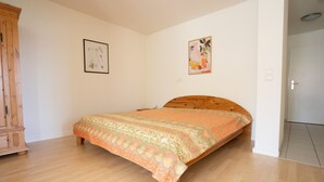 A bedroom with a wooden bed, a wardrobe, and two wall-mounted pictures. - Apartment '1 O G' with Lake View, Balcony and Wi-Fi (Bodman-Ludwigshafen)
