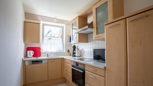 A compact kitchen with wooden cabinets, a built-in oven, and a window providing natural light. - Apartment '1 O G' with Lake View, Balcony and Wi-Fi (Bodman-Ludwigshafen)