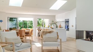 Amplia sala de estar con mesa de comedor, asientos cómodos, cocina equipada con electrodomésticos modernos y chimenea.