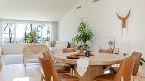 Un moderno comedor con una mesa redonda de madera, sillas de cuero y vistas al exterior a través de amplios ventanales.