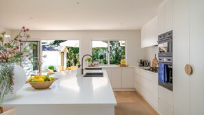 Una cocina moderna con una isla central, armarios blancos y vistas al jardín.