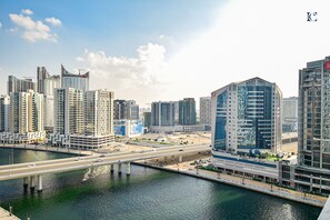 A modern cityscape with high-rise buildings, a river, and a bridge. - Canal View Studio Apt - Maison Prive (Dubai)