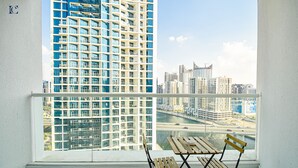 A balcony with a view of high-rise buildings and a river. - Canal View Studio Apt - Maison Prive (Dubai)