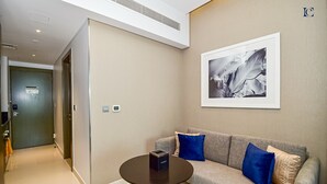 A modern lobby with a sofa, a table, and a framed picture on the wall. - Canal View Studio Apt - Maison Prive (Dubai)