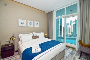 A hotel room with a large bed, a nightstand, a lamp, a chair, and a view of the city through a large window. - Canal View Studio Apt - Maison Prive (Dubai)