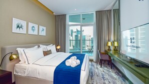 A hotel room with a bed, a TV, a desk, and a view of the city. - Canal View Studio Apt - Maison Prive (Dubai)