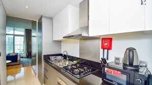 A modern kitchen with a gas stove, a built-in oven, and a coffee maker. - Canal View Studio Apt - Maison Prive (Dubai)