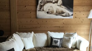 Un salón acogedor con un sofá blanco, una mesa de centro de madera y un cuadro de osos polares en la pared.