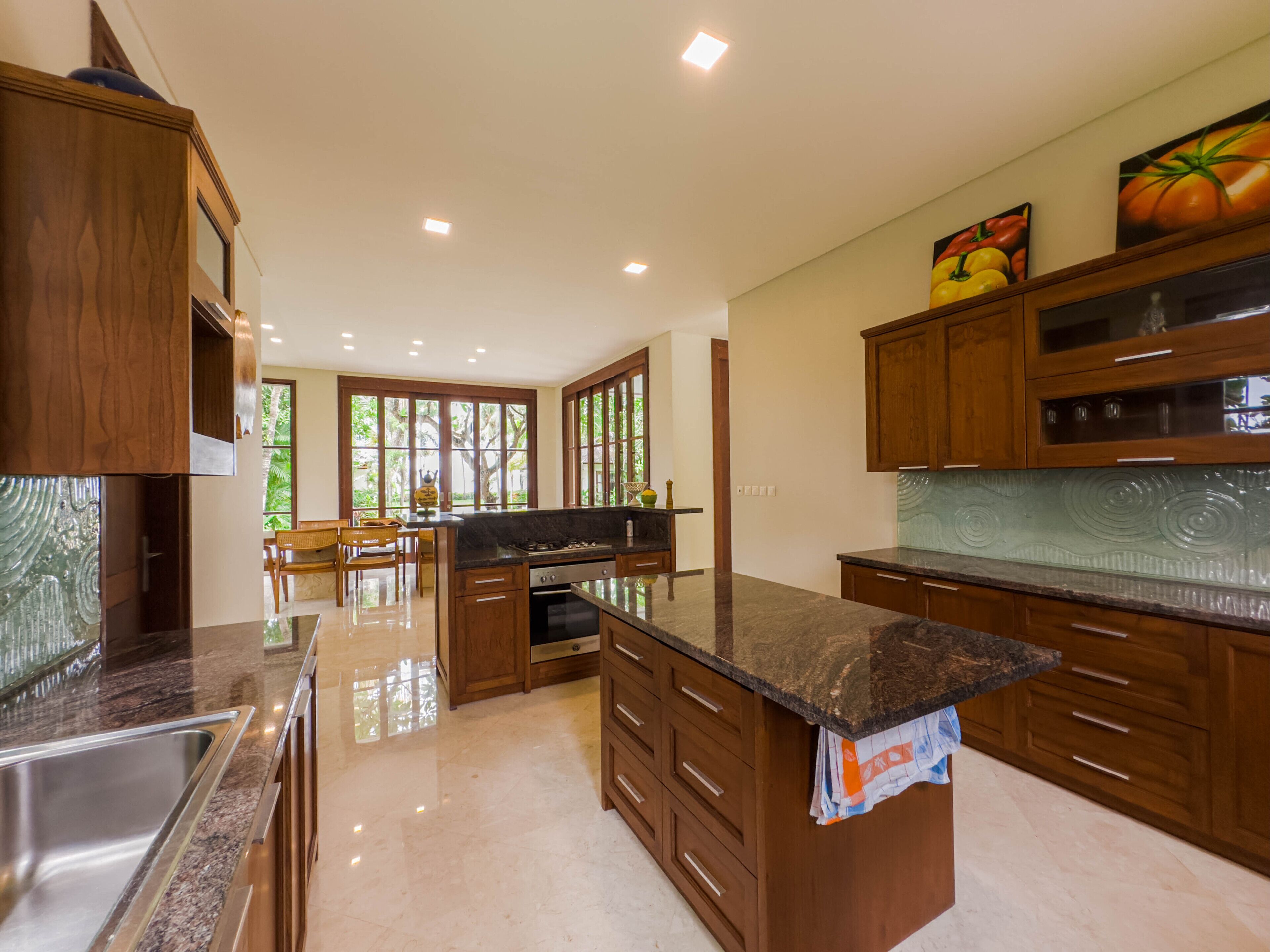 Una cocina moderna con armarios de madera, encimera de granito y pileta de acero inoxidable.