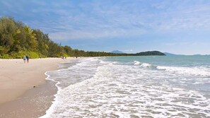 A beach with a sandy shore, gentle waves, and a distant island.
