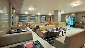Un restaurante con cabinas y mesas, una máquina expendedora y una barra.