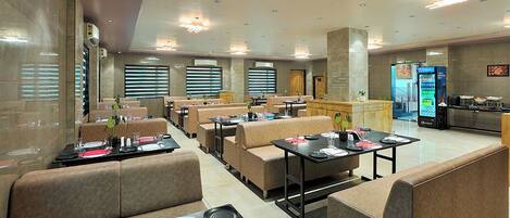 A restaurant with booths and tables, a vending machine, and a counter.