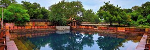 A rectangular pool with a reflection of trees and a clear sky.