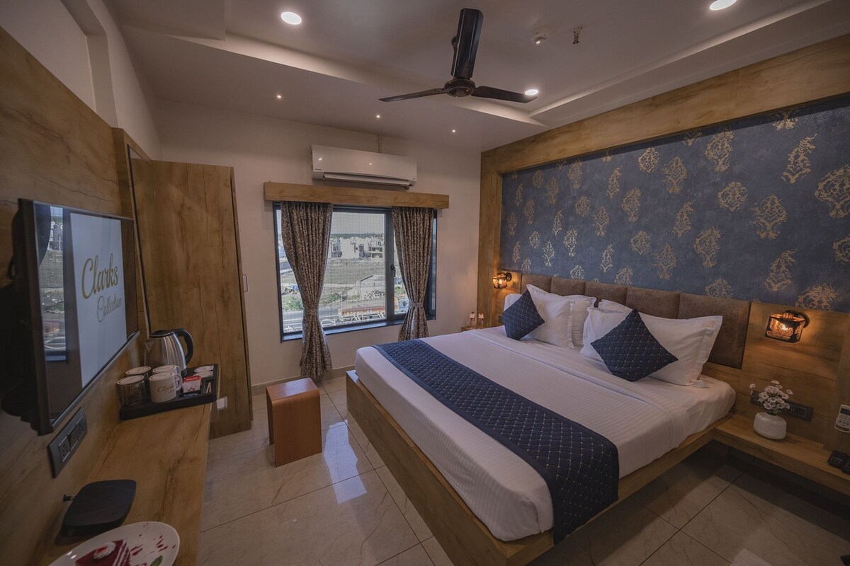 Quarto de hotel moderno com uma cama grande, televisão, comodidades para café e vista para a cidade.