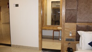 A hotel room with a wooden headboard, a bedside table, a mirror, and a telephone. - Ginger Somnath (Veraval)