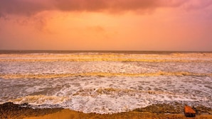 Une plage avec des vagues et un ciel nuageux.